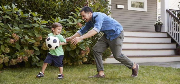 Vater spielt mit Sohn Fuball im bezahlbaren Wohnraum auf dem Land