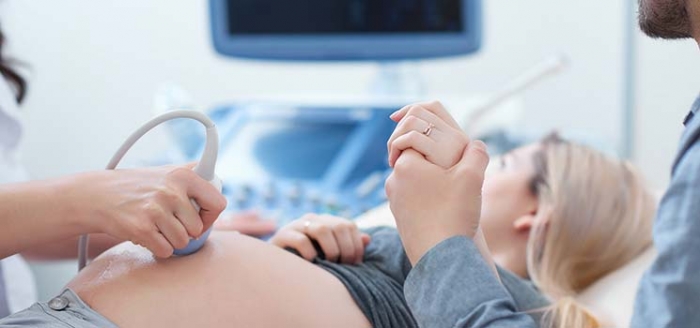 Werdender Vater unterstützt seine schwangere Partnerin beim Ultraschall