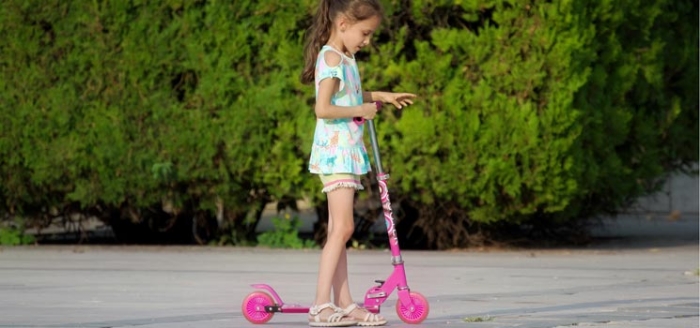Mädchen fährt auf Roller-Scooter und übt sich in Bewegung