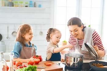 Mutter kocht mit Kindern am Kochtopf
