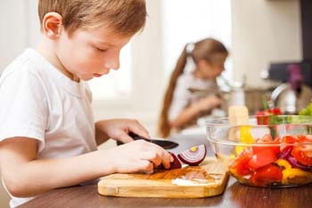 Kinder übernehmen Aufgaben in der Küche und schälen Gemüse